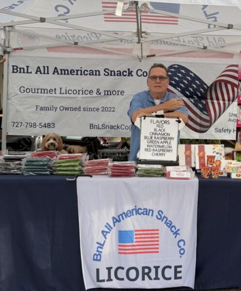Vendor showcasing gourmet licorice and gifts at a patriotic-themed stall.